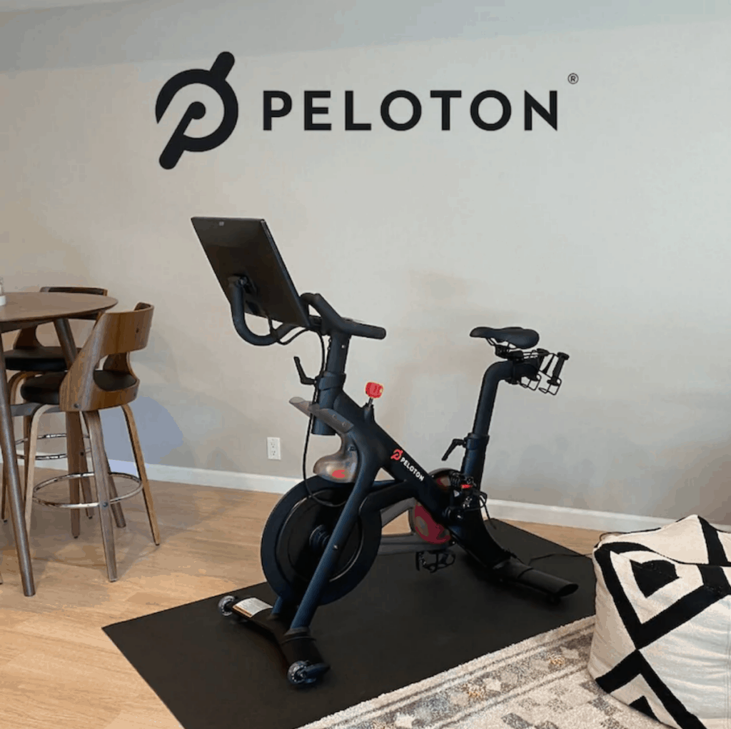 Peloton bike in front of Peloton decal.